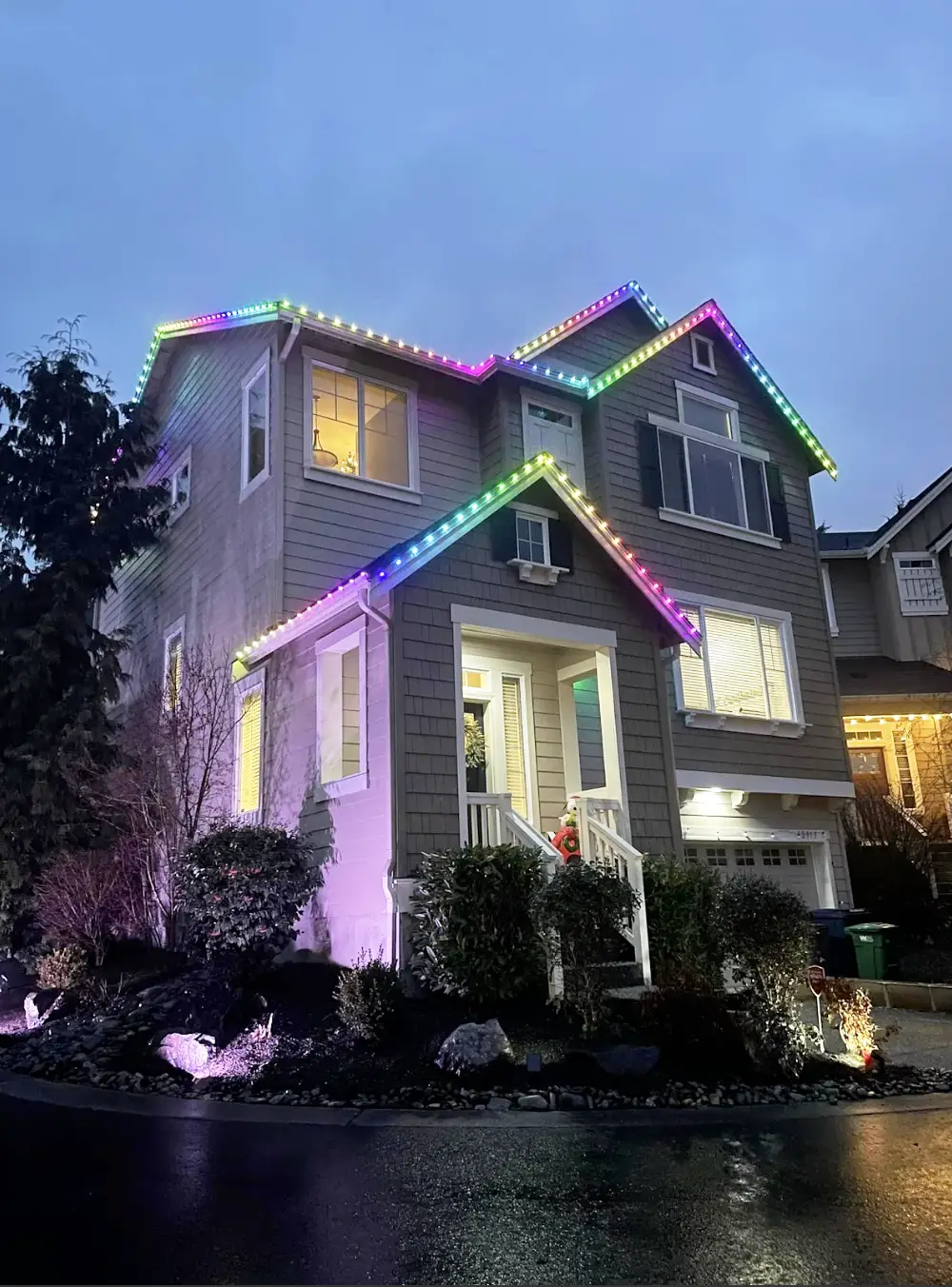 Two-story Utah County home at dusk with Canyon Clear permanent LED lights set to rainbow colors along every roofline