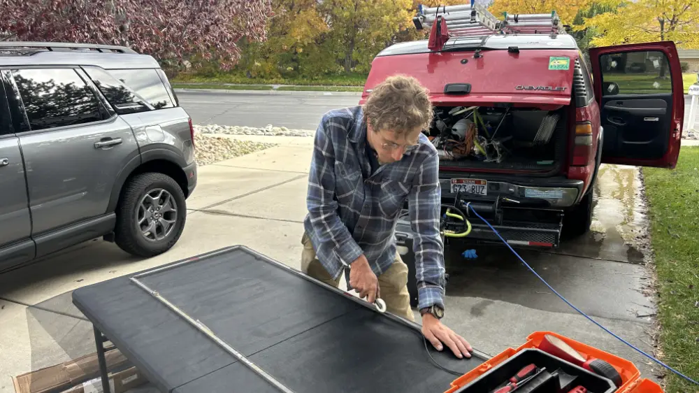Canyon Clear technician rebuilding a window screen on a work table at a Utah County home